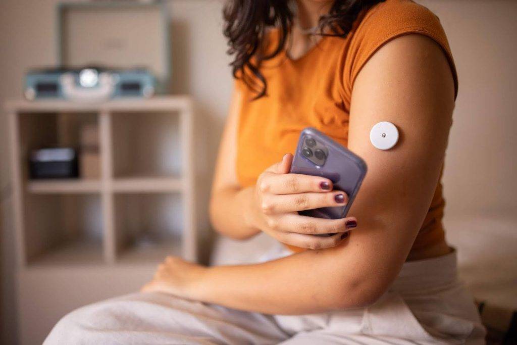 Woman using glucose monitor with phone